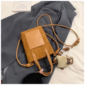 Close-up of brown suede crossbody bag with decorative strap and leopard print plush charm