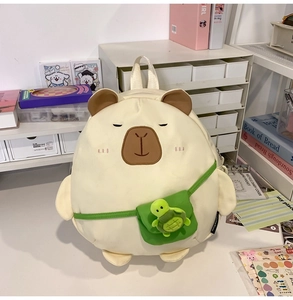Detail of cute beige capybara backpack with a small green turtle charm on a desk