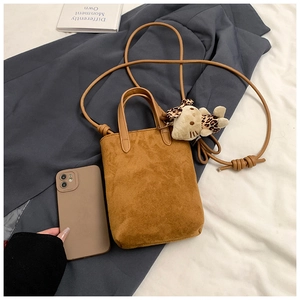 Brown suede crossbody bag with leopard bow charm next to a phone for size reference