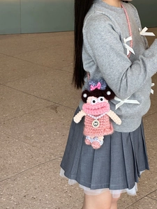 Crochet crossbody bag with pink doll design and pearl necklace detail worn by model