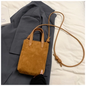 Detailed view of brown suede mini tote with knot shoulder strap on grey blazer