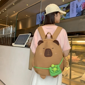 Cute brown capybara backpack with small green turtle pendant shown on model