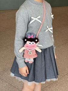 Detailed crochet texture of a pink cartoon shoulder bag worn by a child model