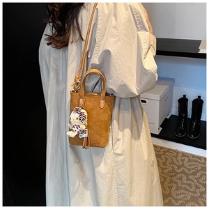 Close-up of camel suede crossbody bag with Hello Kitty leopard bow plush charm on back