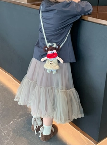 Detailed close-up of a handmade crochet doll shoulder bag with pearl necklace and bow