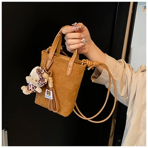 Close-up of brown suede bucket bag featuring a cute leopard print teddy bear charm