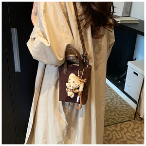 Detail of dark brown suede crossbody bag featuring a leopard print plush charm