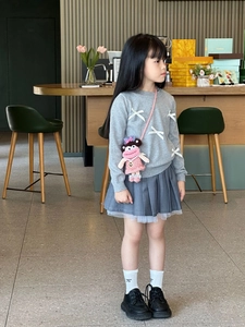 Pink hand-crocheted doll crossbody bag paired with a gray sweatshirt and pleated skirt
