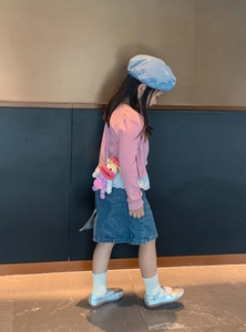 Toddler model wearing a pink knit cardigan and funny crochet sausage mouth doll crossbody bag