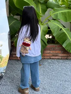 Outdoor shot of a child wearing a brown crochet monster bag with red lips and white flowers