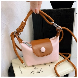 Détail d'un mini sac bandoulière rose et marron avec bandoulière à nœud et texture cuir