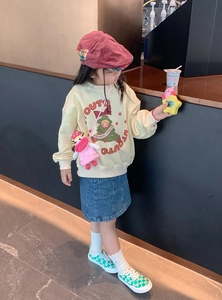Pink handmade crochet doll crossbody bag styled with a yellow sweatshirt and denim skirt