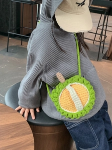 Hand-crocheted durian shaped shoulder bag for children worn by a young model