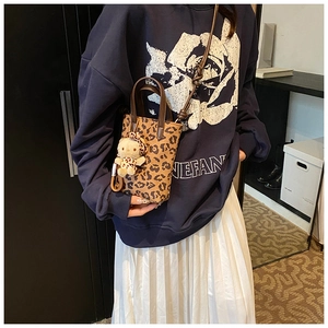 Detail of leopard print crossbody bag with mini bear charm and adjustable strap