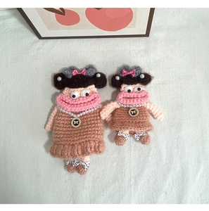 Detail of two handmade crochet doll shoulder bags with funny lips and pearl necklaces