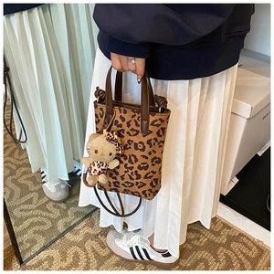 Detail of leopard print tote bag featuring a cute feline charm and premium leather straps