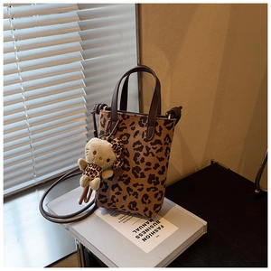 Close-up of leopard print mini bucket bag with leather strap and plush cat charm