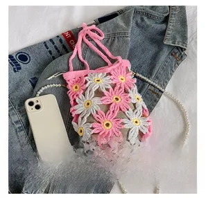 Detail showing handmade crochet floral bag size comparison with a smartphone and pearl strap