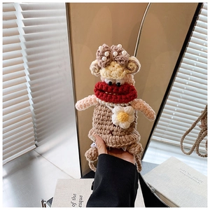 Close-up of handmade crochet ugly-cute doll bag with pearl necklace and flower accessory