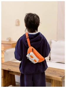Detalle de un bolso de pecho infantil naranja con forma de coche usado por un niño