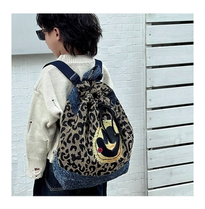 Détail du sac à dos léopard avec bordure en denim et écusson smiley jaune brodé