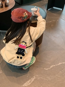 Close-up of a handmade crochet doll crossbody bag with knitted hat and yellow sweatshirt