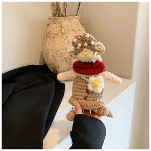 Detail of handmade crochet monkey bag with pearl necklace and knitted scarf for children