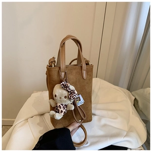 Detail of suede shoulder bag with leopard bow plush cat charm and dual handle strap