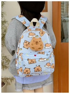 Détail du sac à dos bleu clair avec imprimés capybara et breloque en peluche 3D