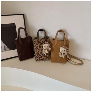 Detailed view of leopard print and suede crossbody bags with cute plush charms