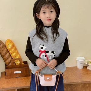 Mini sac bandoulière enfant bicolore rose et marron en similicuir sur table en bois