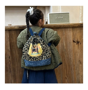 Vue arrière d'un enfant portant un sac à dos léopard avec une base en denim bleu
