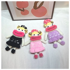 Detailed view of handmade crochet doll keychains in black, pink, and purple yarn