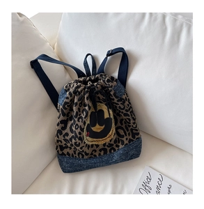 Détail du sac à dos léopard avec patchwork de denim bleu et patch visage souriant jaune