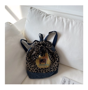 Détail d'un sac à dos imprimé léopard avec bordure en denim et écusson chat mignon
