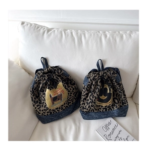 Détail de sacs à dos en toile léopard et denim avec écussons de dessins animés et cordon