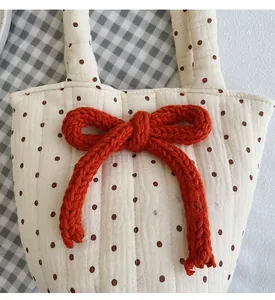 Close-up of quilted cotton tote bag featuring polka dot pattern and large red knitted bow