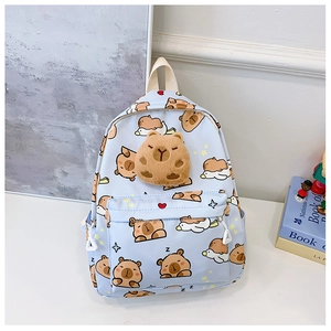 Détail d'un sac à dos bleu clair avec imprimés capybara et décoration en peluche