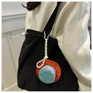 Detail einer schwarzen Nylon-Tasche mit Kordelzug und buntem Smiley-Anhänger-Mini-Geldbeutel