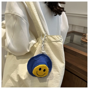 Detail der blauen Anglerhut-Mini-Geldbörse mit gelbem Smiley-Gesicht und Metallclip