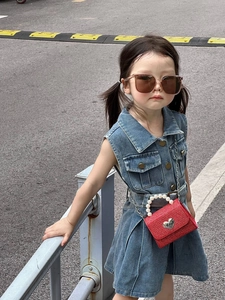 Détail du mini sac rouge avec fermoir cœur et anse en perles sur une robe en jean