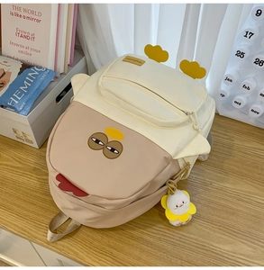 Detail of cute cartoon backpack with quirky face design and white duck plush keychain