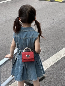 Fillette avec petit sac rouge en tweed, poignée en perles et fermoir en forme de cœur