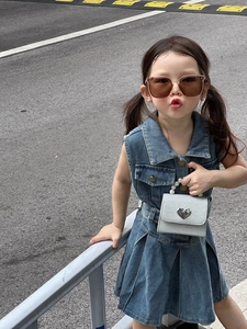 Détail d'un mini sac argenté avec poignée en perles et fermoir cœur sur robe en jean