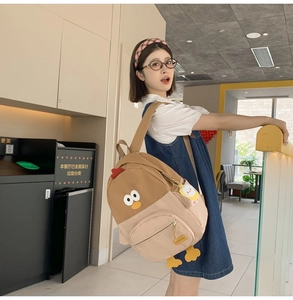 Detail view of cartoon chicken backpack with 3D comb, eyes, and hanging feet decorations