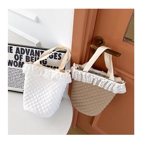 Detail einer gesteppten Baumwolltasche mit feiner Spitze und weichen Pompon-Details