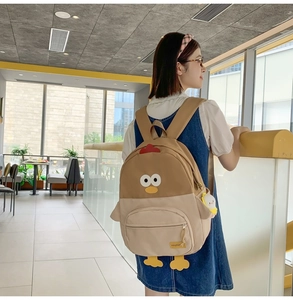 Detail of cute cartoon chicken backpack featuring soft plush wings and red comb accents