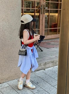 Close-up of children's black mini crossbody bag styled with trendy casual outdoor outfit