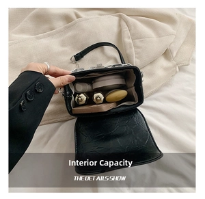 Internal view of a mini black crossbody bag with lipstick, compact powder and phone