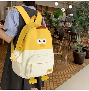 Detailed close-up of cartoon chick backpack with plush charm in cozy cafe setting